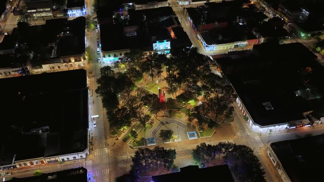 Aerial orbit surrounding Plaza de la Heroes in Villarrica city center and Municipality (city hall) colonial building, Paraguay, at night