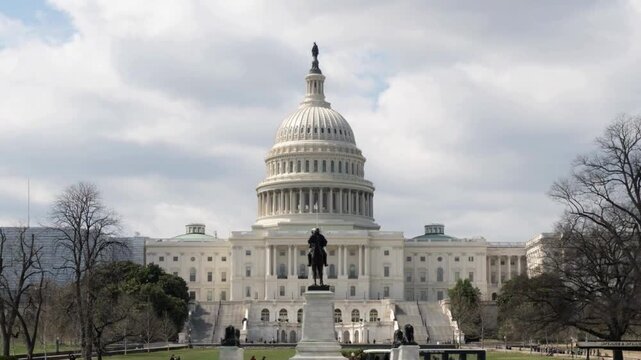 United States Capitol building with moving clouds in Washington DC during bright sunny day showing grand white architecture and Ulysses S Grant memorial.