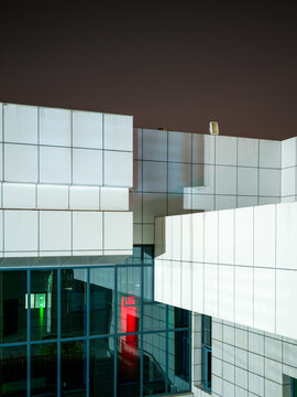 Geometric modern building structure with white panels and green and red lights at night