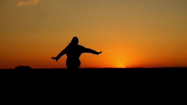 Silhouette of girl running across field during vivid sunset outdoors. Freedom, childhood, happiness and carefree lifestyle concept in nature at golden hour.