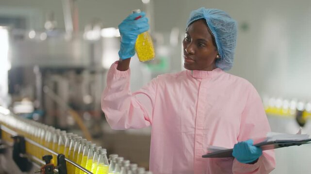 Quality Control Inspection: An focused employee performs quality control inspection of liquid substance in factory.
