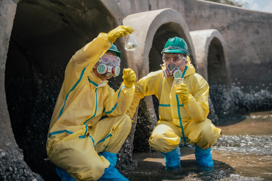 Field researchers wearing safety gear gather polluted water samples from industrial drainage systems to evaluate contamination risks, and long-term environmental protection strategies.