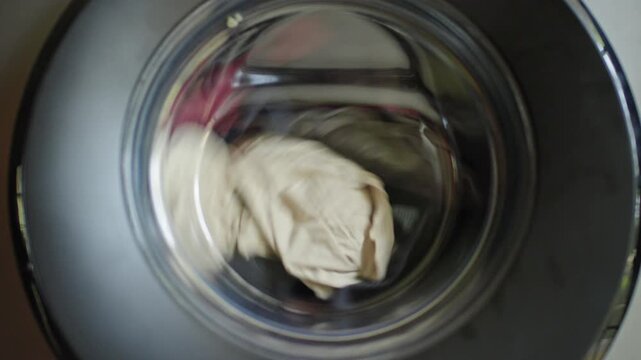 A close up view of a washing machine drum spinning with a load of clothes during a wash cycle.