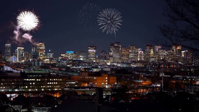 Breathtaking cinematic footage showing night skyline of Boston city illuminated by colorful pyrotechnics show display exploding during holiday celebration.