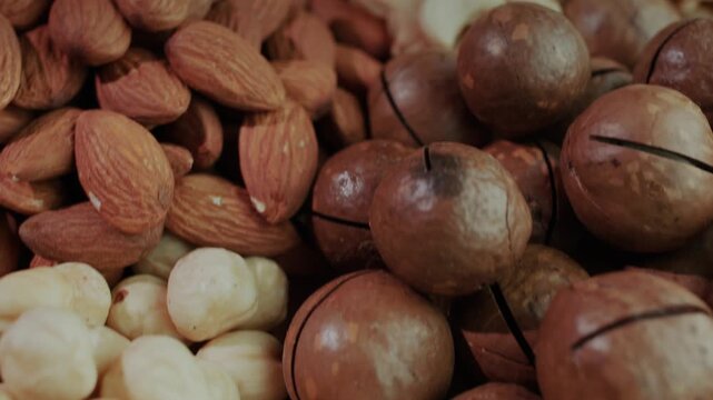 A captivating close up view of assorted nuts slowly rotating, showcasing the rich textures and colors of almonds, cashews, pistachios, and macadamia nuts in dynamic motion.