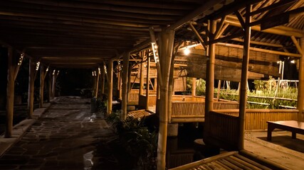 Luxury bamboo lodge pathway glowing under warm night lights with tropical architecture and peaceful resort atmosphere, ideal for vacation, wellness, and eco tourism themes. © Entas