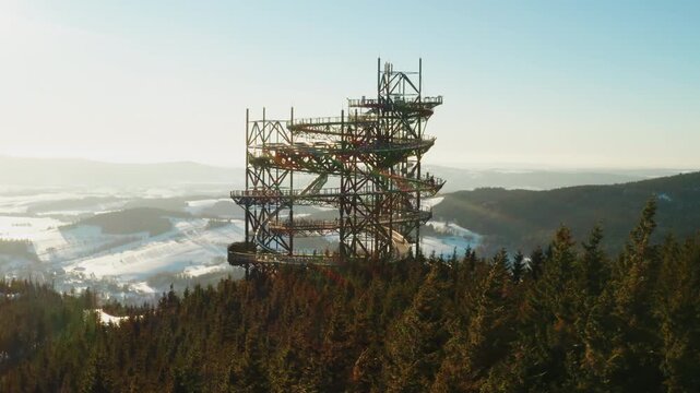 Winter aerial view of the Sky Walk tower towering above a snow-covered mountain valley in Dolni Morava, Czech Republic.