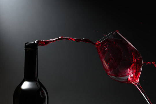 Red wine of rich color being poured from a bottle into a glass.