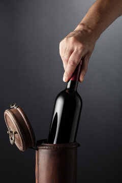 Sommelier places a bottle of red wine in an old wooden box.