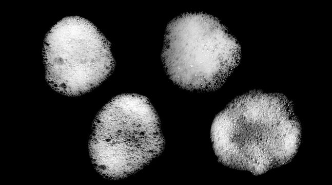 White soap foam bubbles isolated on black background. Cleaning texture with detergent suds for hygiene, washing, sanitation and cosmetic product design concept.