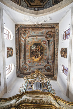 View of the ornate pipe organ and religious frescoed ceiling inside a historic church in Polignano a Mare, Apulia, Italy.