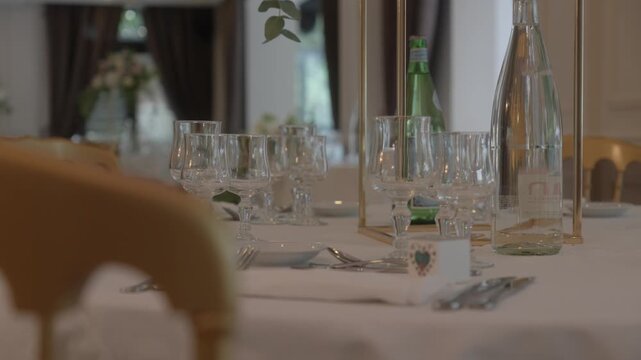 Panning shot of elegantly set table with glassware, plates and decorations for wedding reception