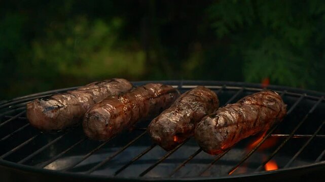 Close-up sausages on bbq grill, cooking hot dogs, slow motion grill fire flame