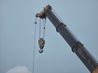 Construction crane boom and hook against cloudy sky with heavy machinery ©  Hussan