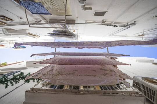 View of laundry hanging on lines between traditional white buildings in a narrow alleyway Polignano a Mare, Apulia, Italy.