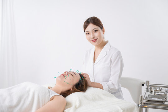 美容鍼灸する女性と鍼灸師