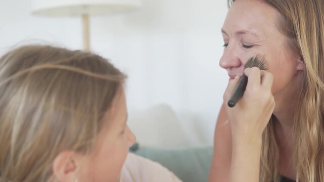 daughter makes machijah to her mother at home, Girl emphasizes the cheekbone line of her mae with the help of applying blush.