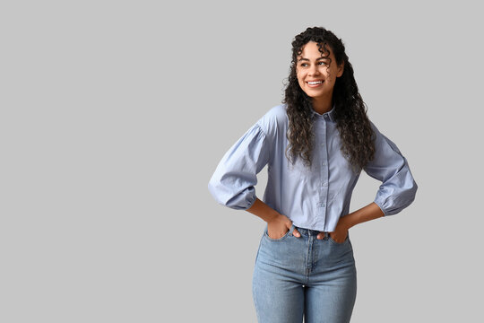 Beautiful young African-American woman in stylish blue collar shirt on grey background