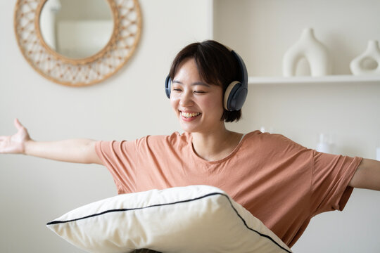 部屋でヘッドフォンをして音楽を聴いている女性