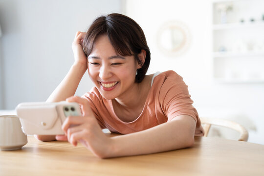 家でスマホで動画鑑賞をしているショートカットの女性