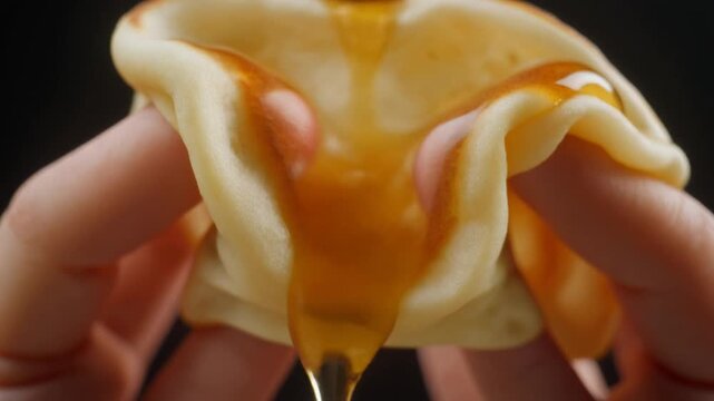 指で押し潰されるパンケーキとはちみつのシロップ。リアルな質感と癒やしのマクロ映像