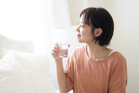 グラスに入った水を持って微笑んでいるショートカットの女性