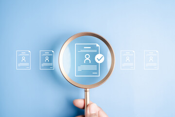 Obraz na płótnie Canvas Human resources recruitment and hiring the right job candidate. Hand holding magnifying glass over resume document icon with checkmark for approval.