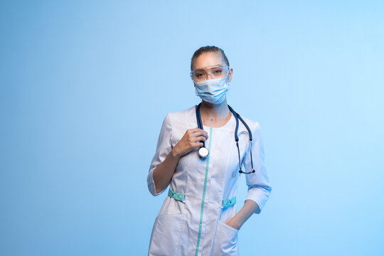 Medical worker standing, looking at camera, wearing protective equipment and scrubs, symbolizing health and protection
