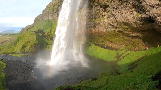 Cinematic 4K shot of tourists walking behind Seljalandsfoss waterfall