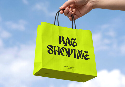 Hand Holding Paper Shopping Bag Mockup with Sky Background