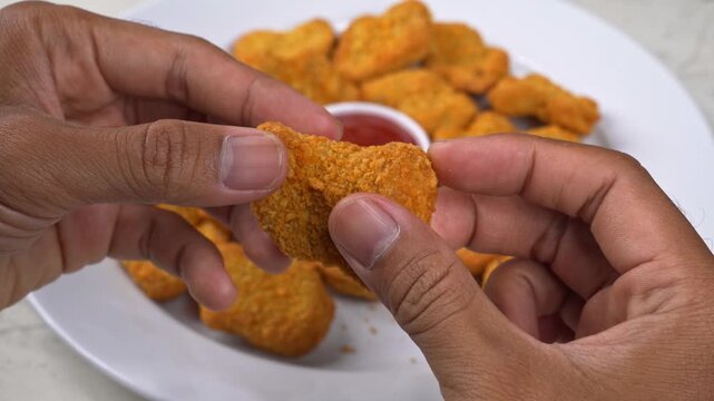 Top-down view of hands tearing apart a crispy fried chicken nugget revealing textured meat inside