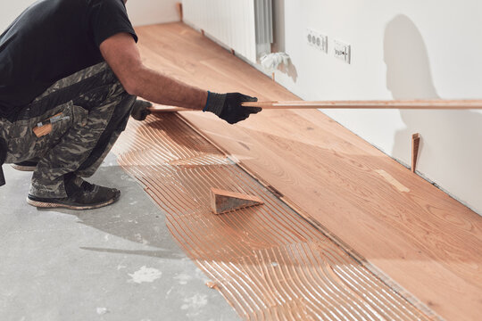 Professional handyman installing laminate flooring in a new apartment.