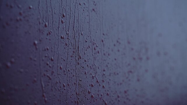 Rain drops flowing down window glass during cloudy weather