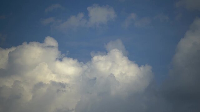 White cumulus clouds move across a blue sky on a sunny day