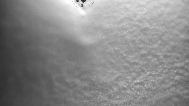 White soap foam washing over a black surface creating atmospheric streaks and textures