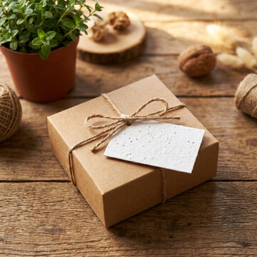 Rustic ecofriendly brown cardboard gift box with white tag on wooden table