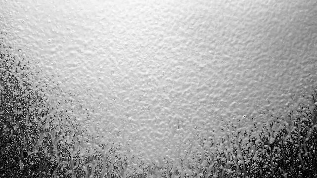 White foam and tiny particles spraying across a dark black background