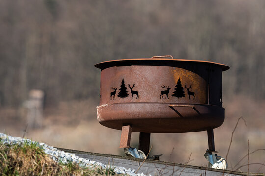 Rusty steel fire pit ring with cutout deer and pine tree silhouettes in winter Wachau