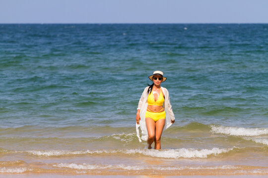 Woman with yellow bikini walk on beach