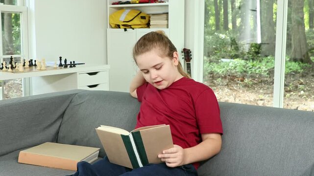 Reading book supports child education. Kid read book quietly indoors. Child reading book with concentration. Kid reading book during homeschool.
