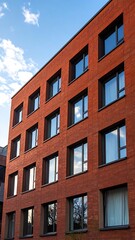 Obraz premium A red brick building with multiple windows under a blue sky