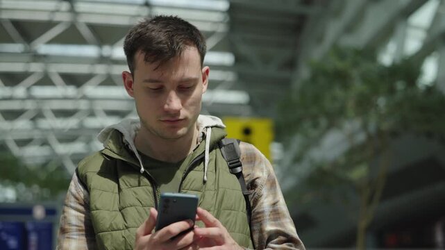 Young traveler using smartphone while waiting inside modern airport terminal