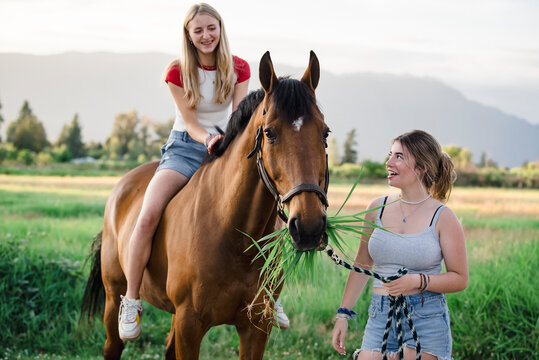 Two teen girls and a horse smiling and laughing