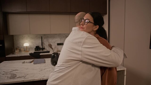 Handheld shot of Caucasian man putting resident keys on divorce agreement and hugging his ex wife, taking suitcase and leaving apartment