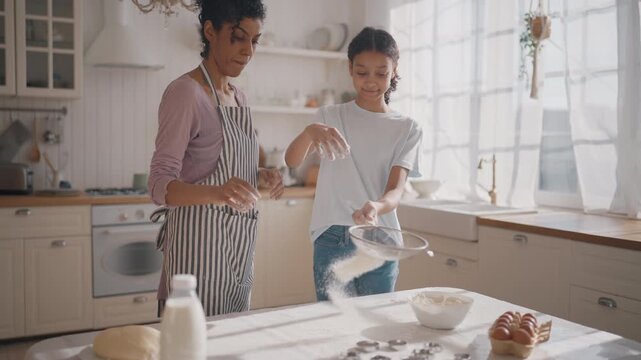 African american mom and daughter cooking together in weekend, baking cookies. Happy family spending time together, single mother and her teen child making dough for pie or cake for family fest