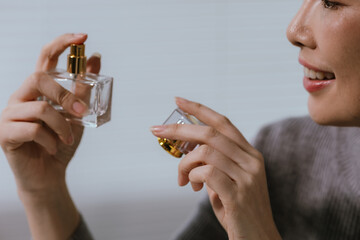 Fototapeta premium Young Asian woman smelling perfume from a luxury fragrance bottle, expressing elegance, beauty, and personal care in a modern lifestyle setting.