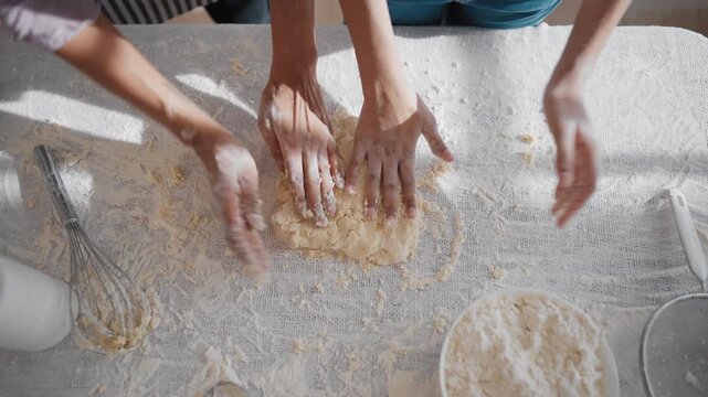 Woman and daughter making pie in heart shape, closeup view of hands, mother day. Top view on table top with female hands and dough for cake or cookies, traditional homemade dish for christmas holiday