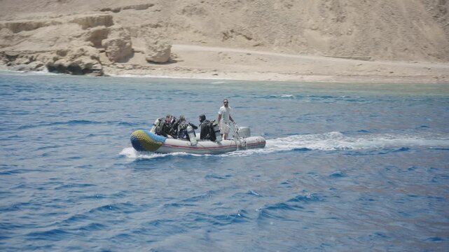 Group of scuba divers in full gear sailing on a rigid inflatable boat in the open ocean