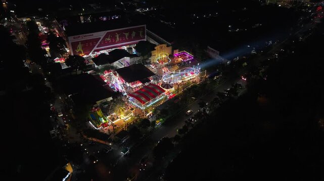 Aerial view of GOR Gelarsena Klaten Night Market with illuminated fairground rides and carousels at night in Kecamatan Klaten Utara, Jawa Tengah, Indonesia.