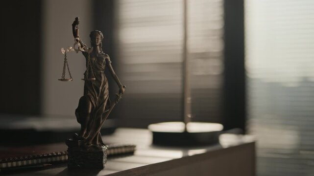 Close up of statue of Themis on top of wooden table in lawyers office lit by natural light